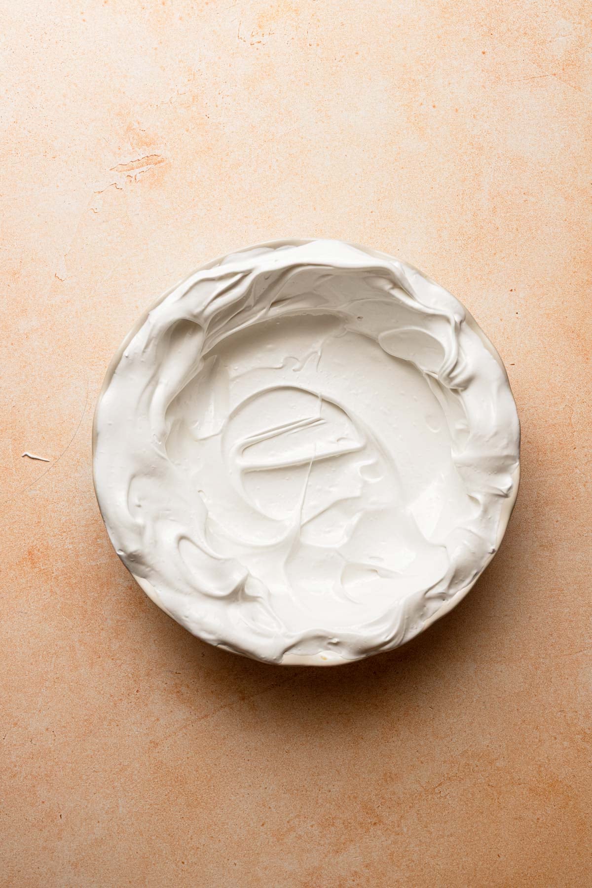 A pie dish with raw meringue.