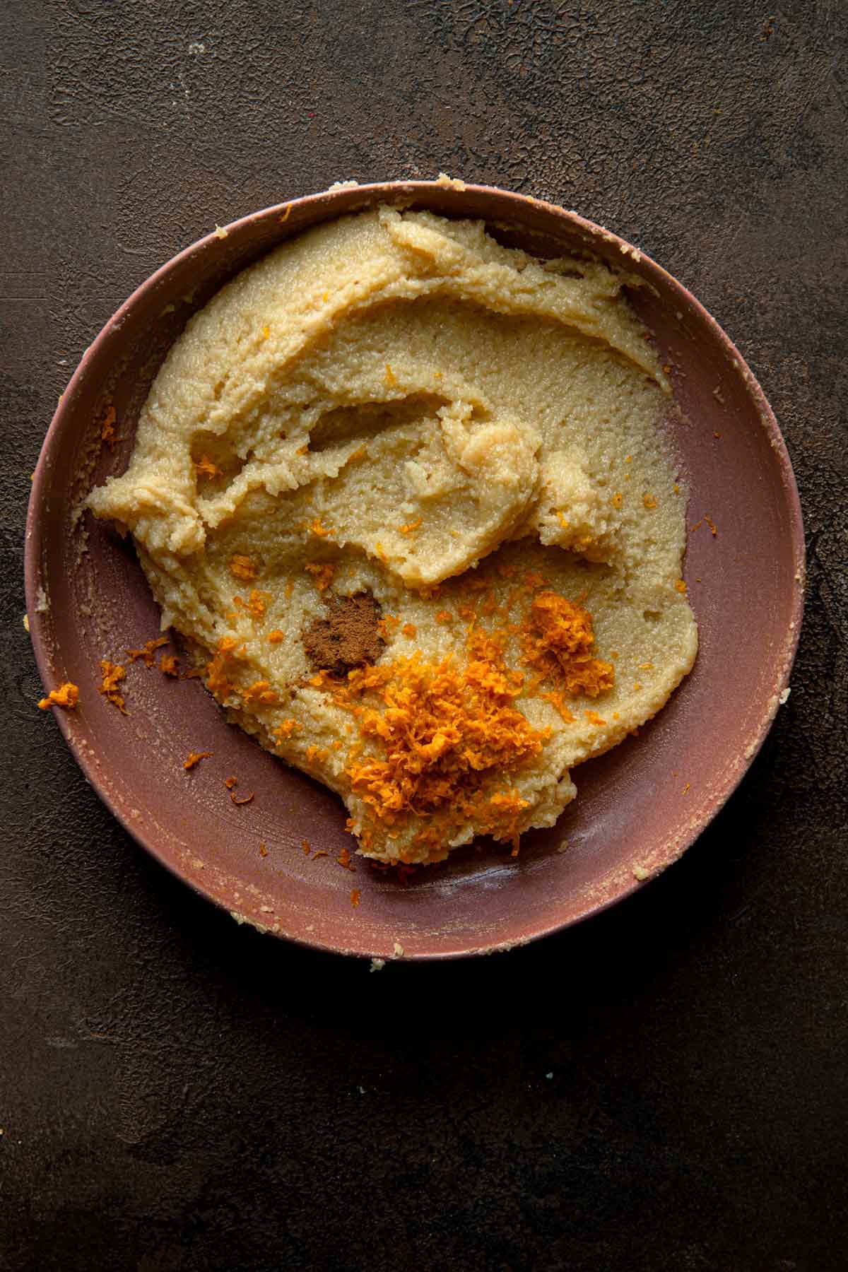 A bowl with almond cream, orange zest and ground cinnamon.