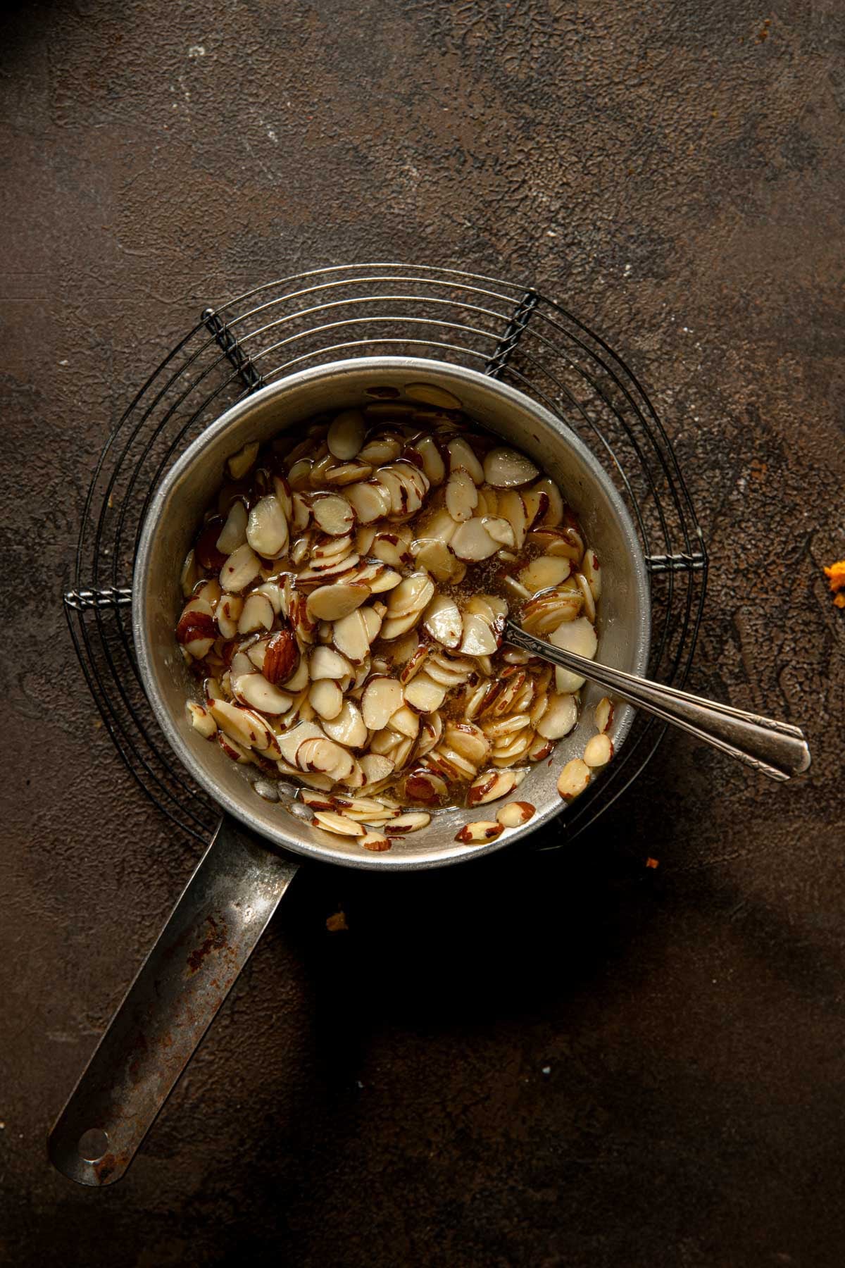 A sauce pan over a cooling rack with honey and almond mixture.