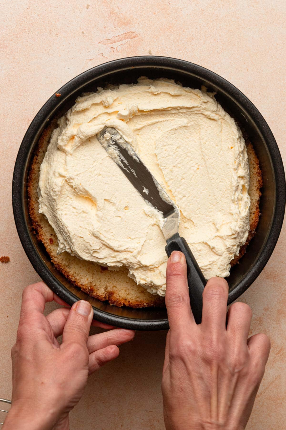Hands spreading cream over sliced brioche.