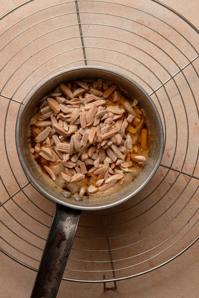 A sauce pan with honey and almonds.