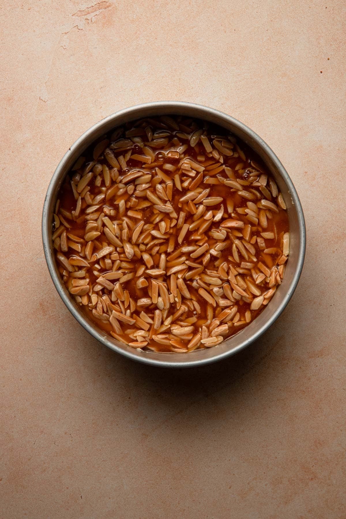 A pan with dough topped with almond and honey mixture.