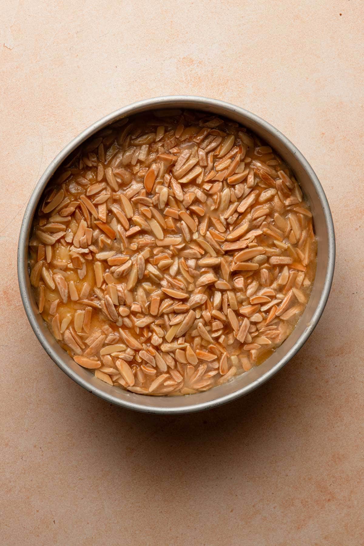 A pan with proofed dough topped with almond and honey mixture.
