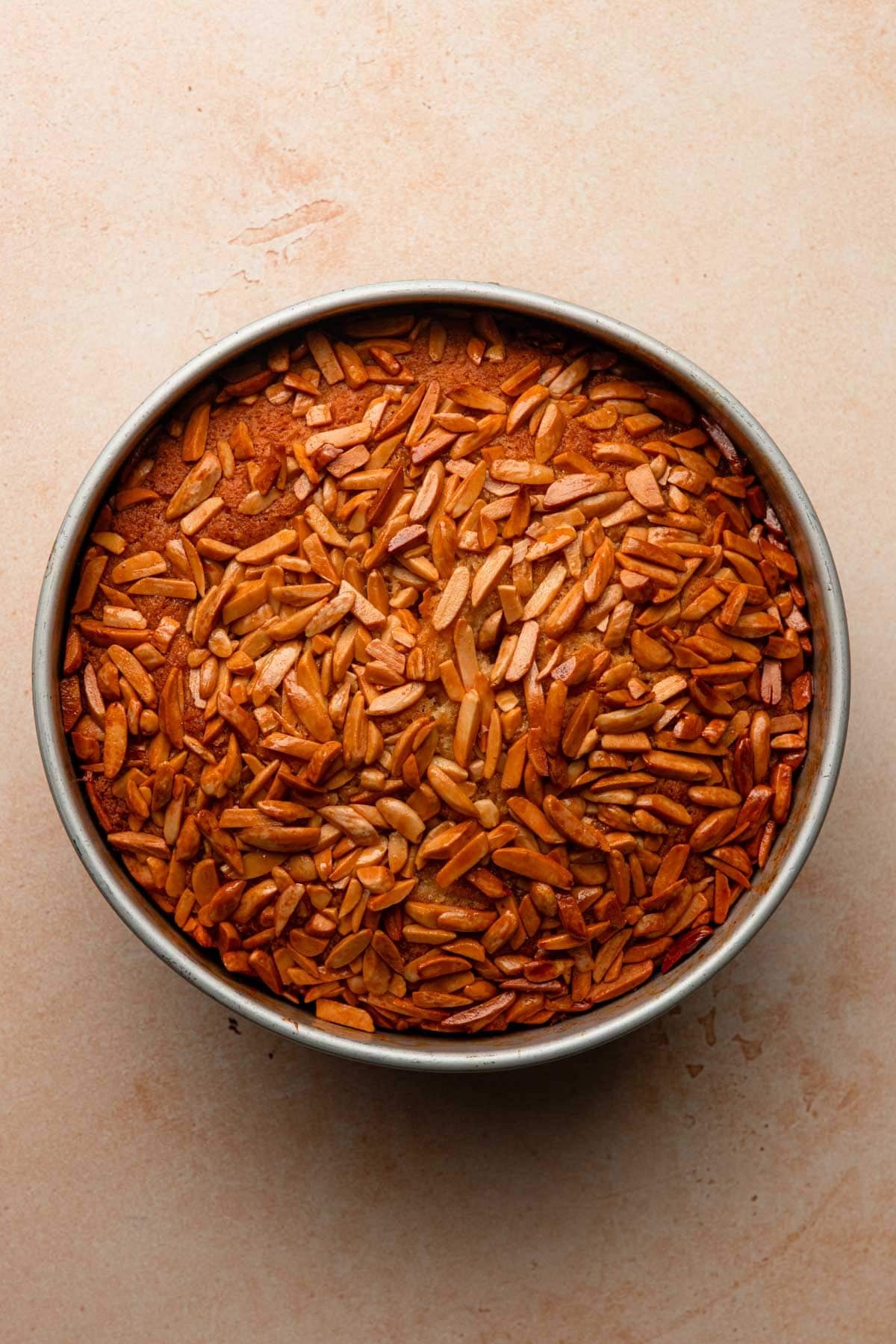 Baked brioche in a cake pan topped with almonds.