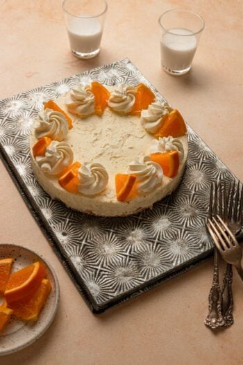 no bake orange cheesecake topped with whipped cream and slices oranges.