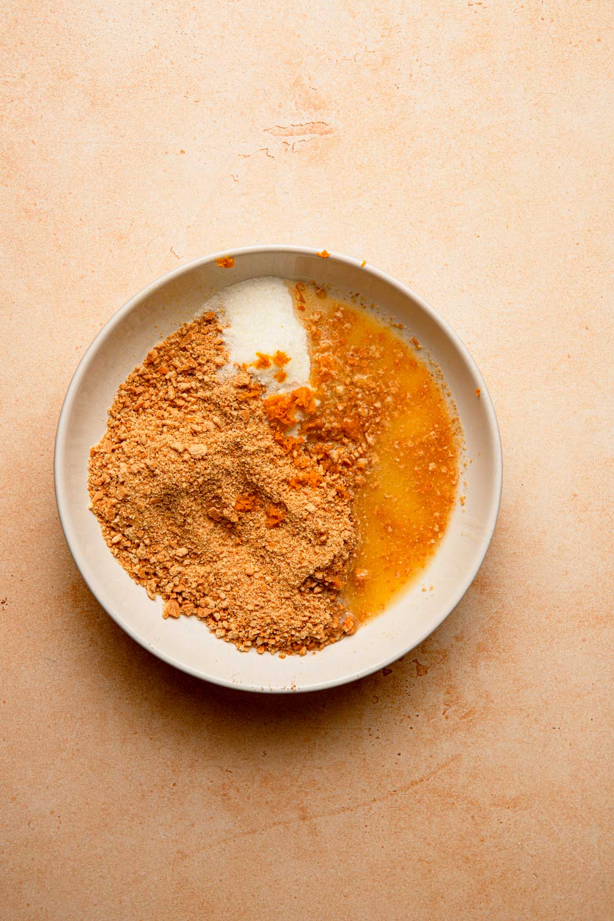 A bowl with cookies crumbs, and orange zest.