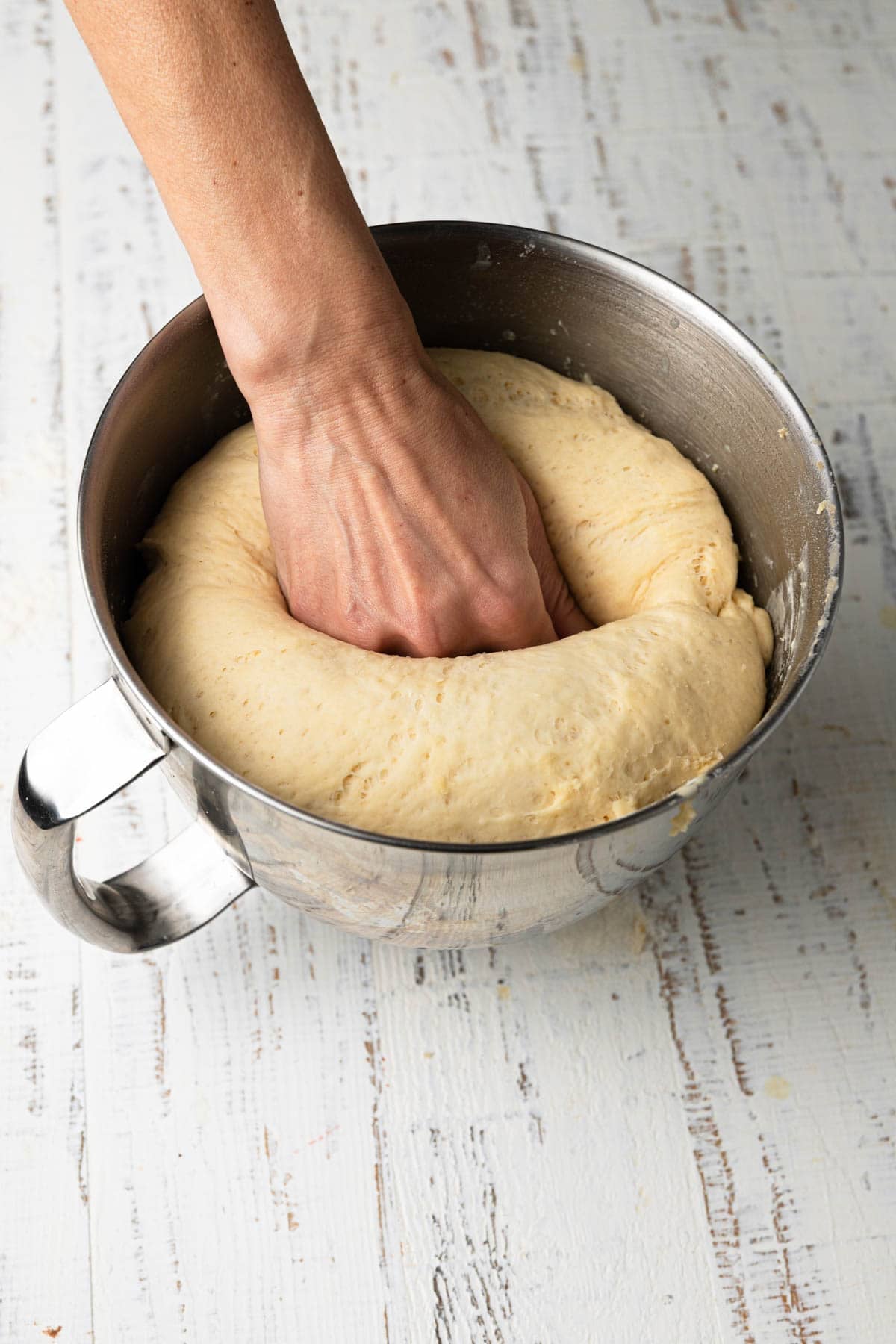 A hand deflating sweet rolls dough.