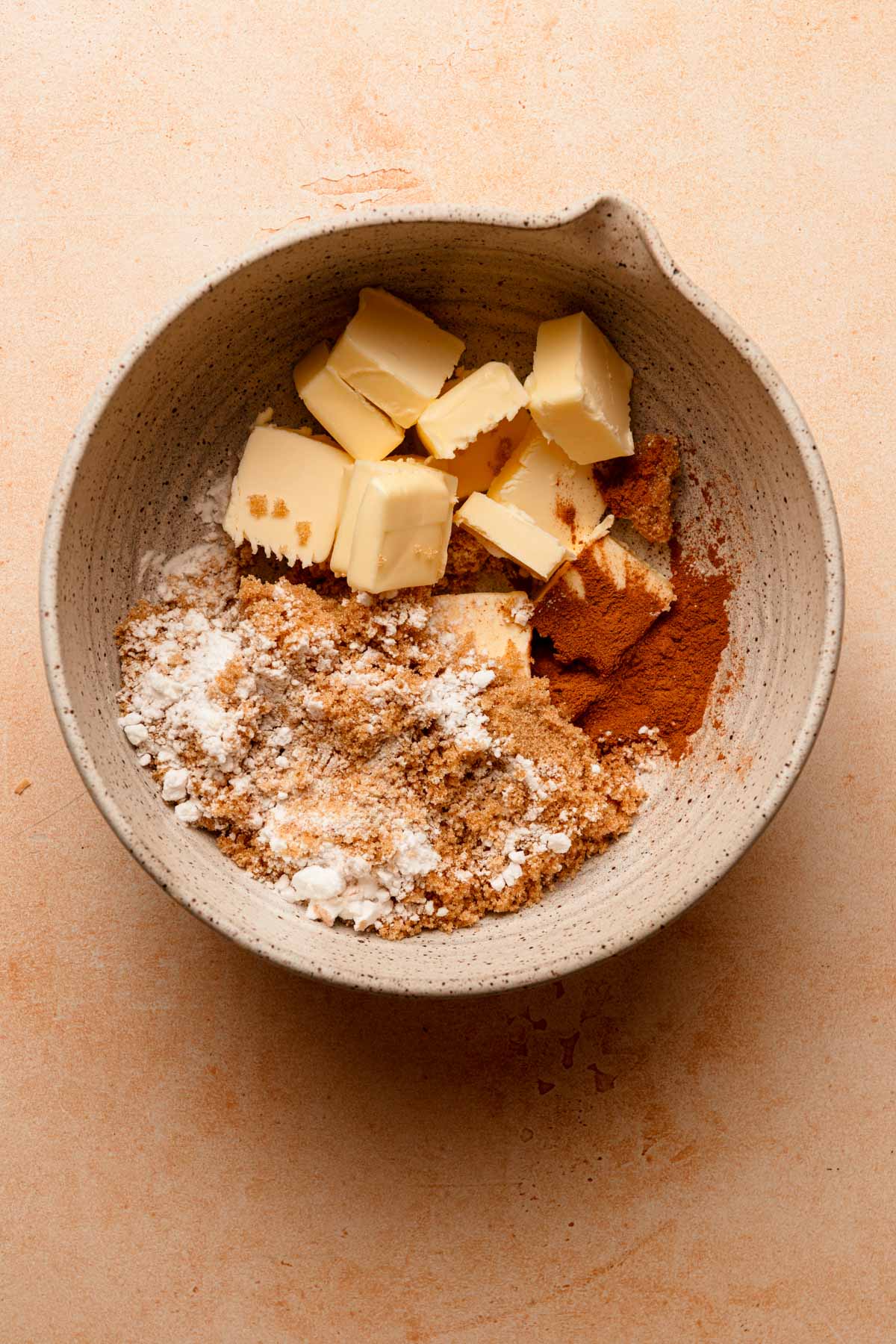 A large bowl with light brown sugar, potato starch, ground cinnamon, and butter.
