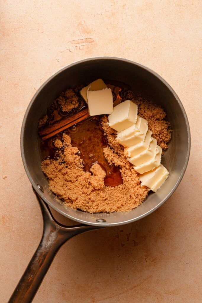 A sauce pan with butter, honey, sugar and a cinnamon stick.