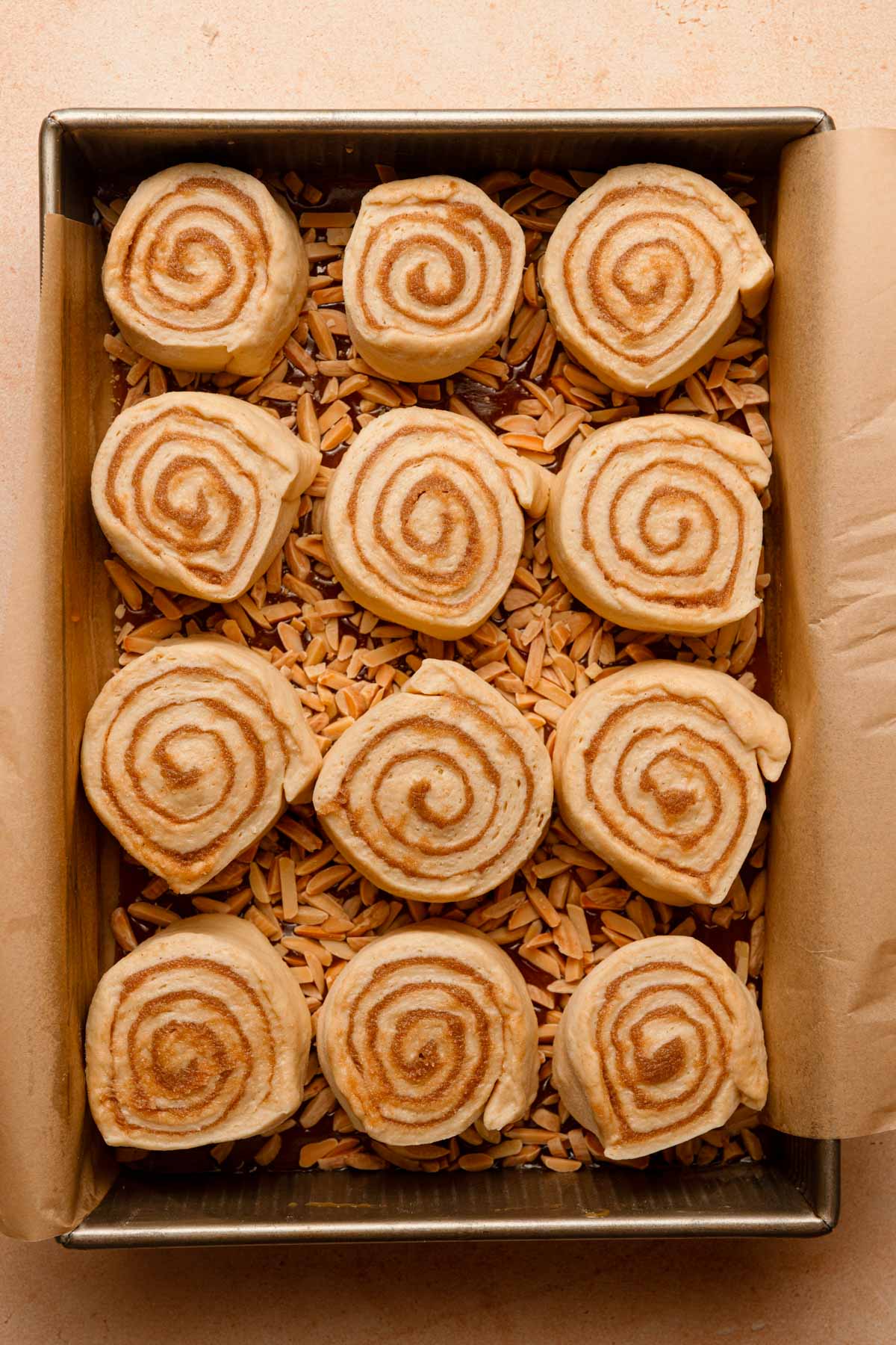 Unbaked cinnamon roll topped over chopped nuts in a pan.