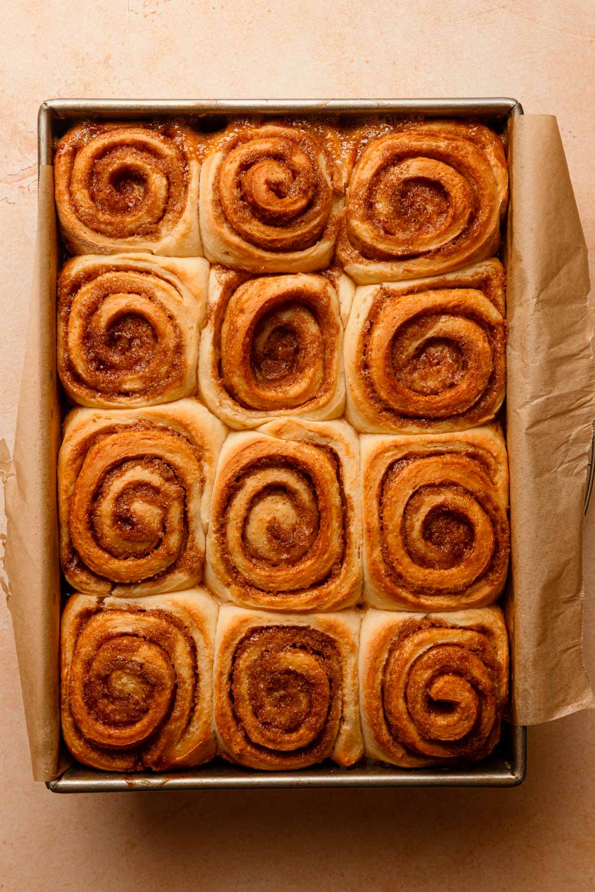 Baked cinnamon rolled in a pan lined with parchment paper.