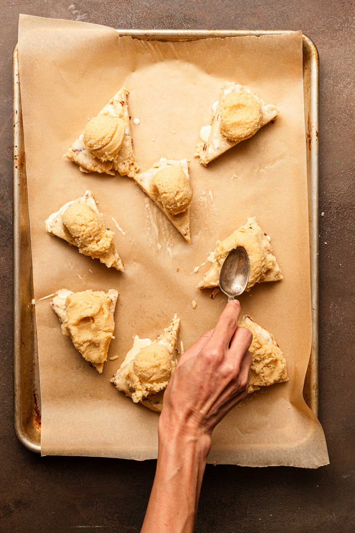 Spreading almond paste over unbaked pastries.