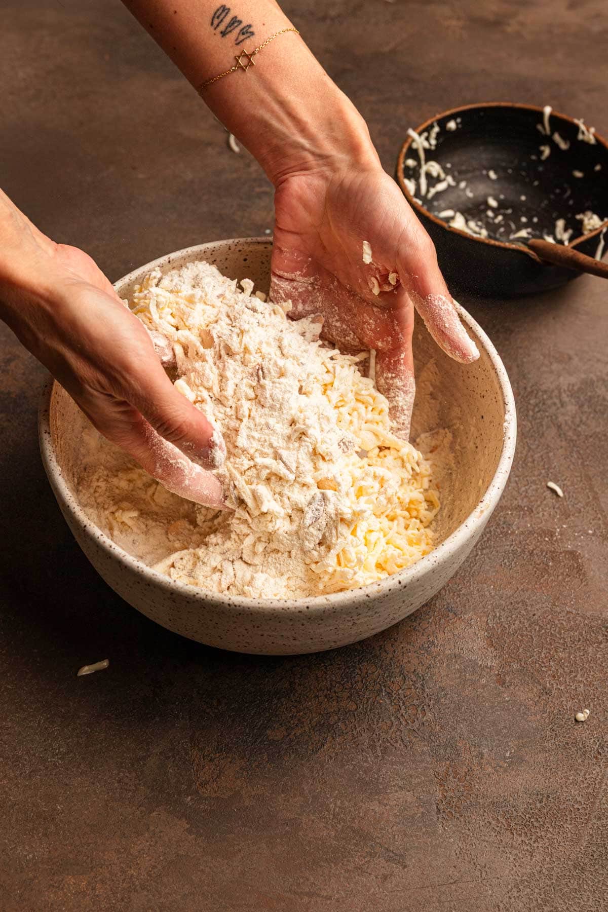 Tossing grated butter into flour in a large bowl.