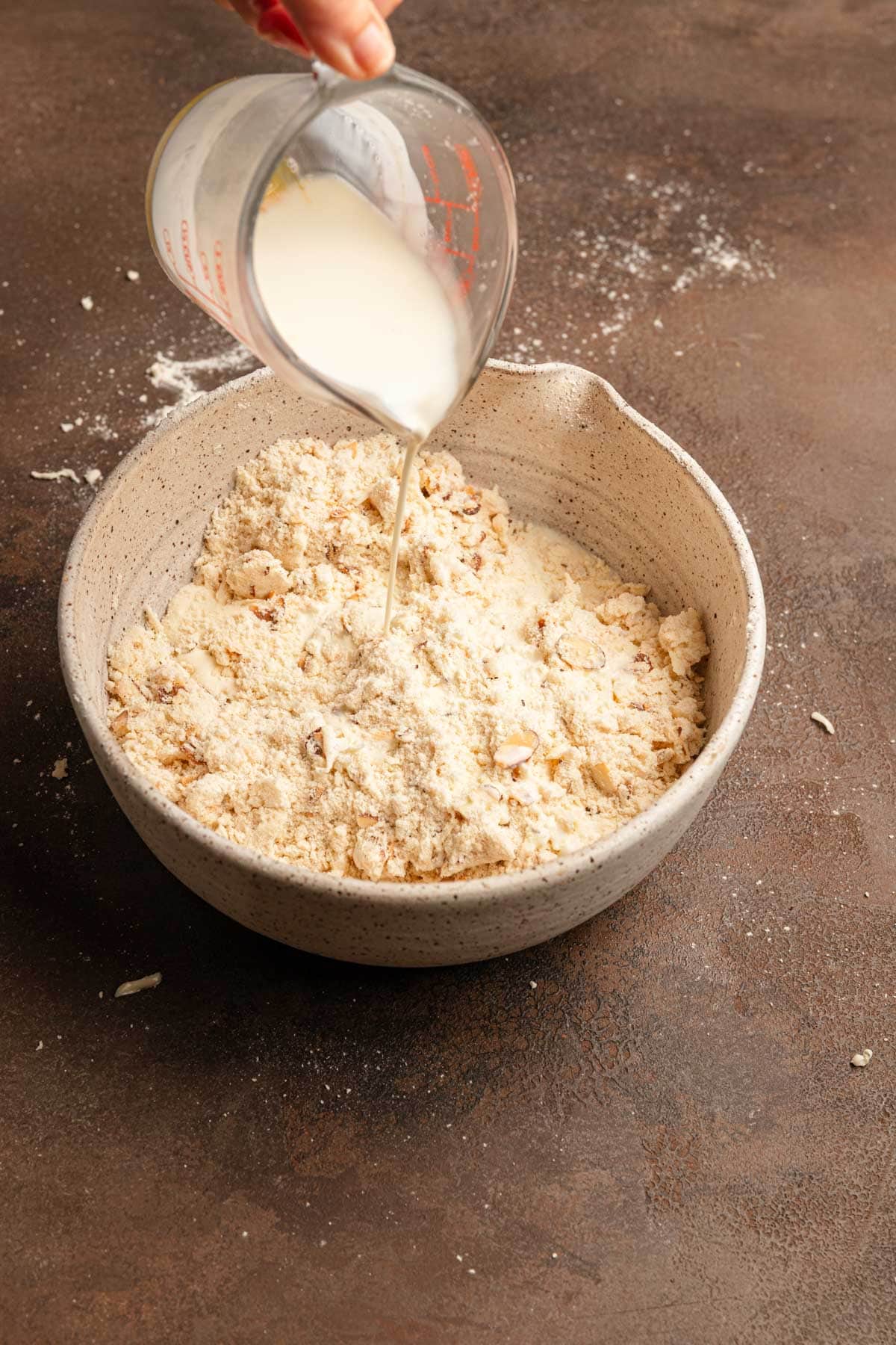 Pouring cream over flour mixture in a a large bowl.