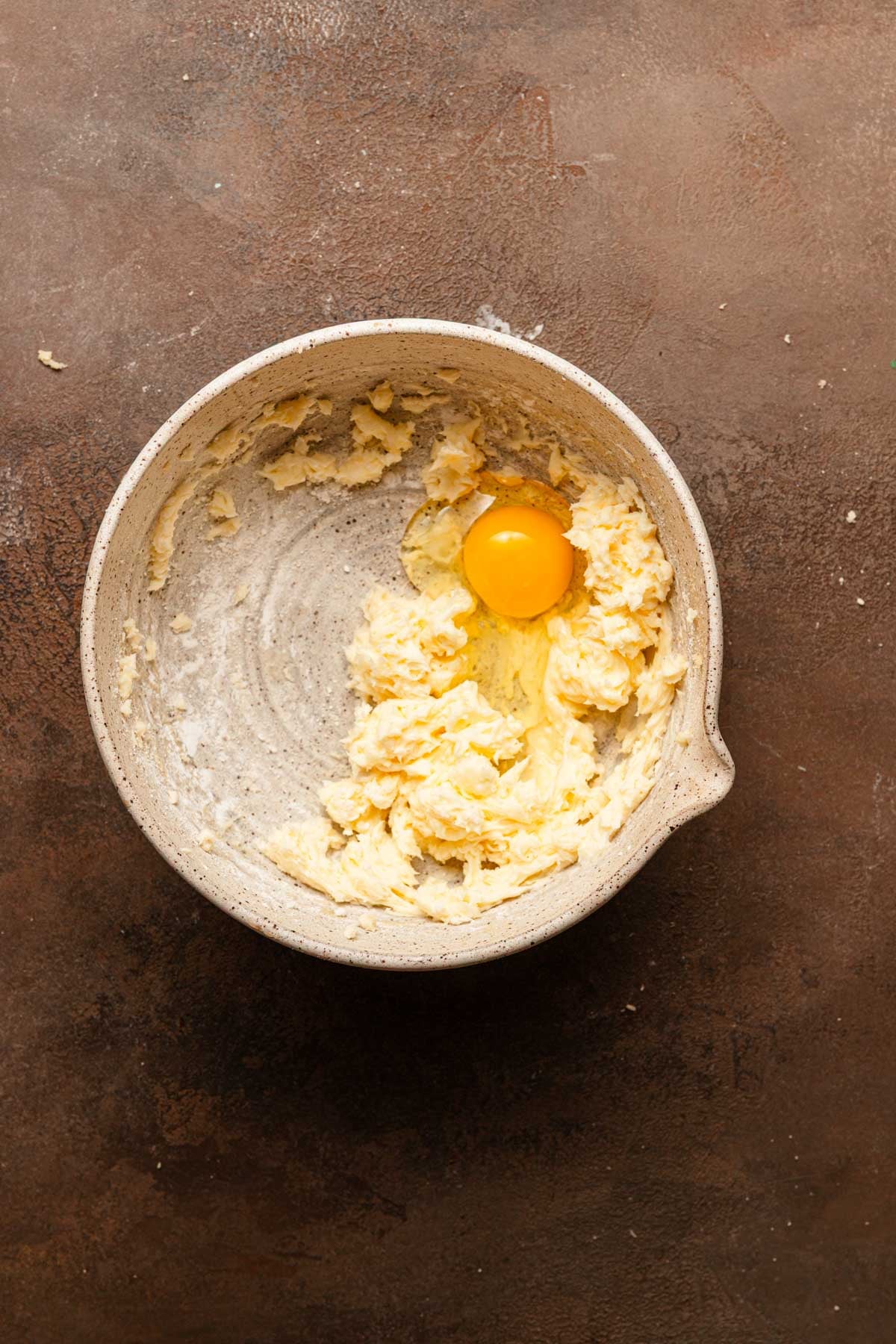 A mixing bowl with creamed butter and an egg.