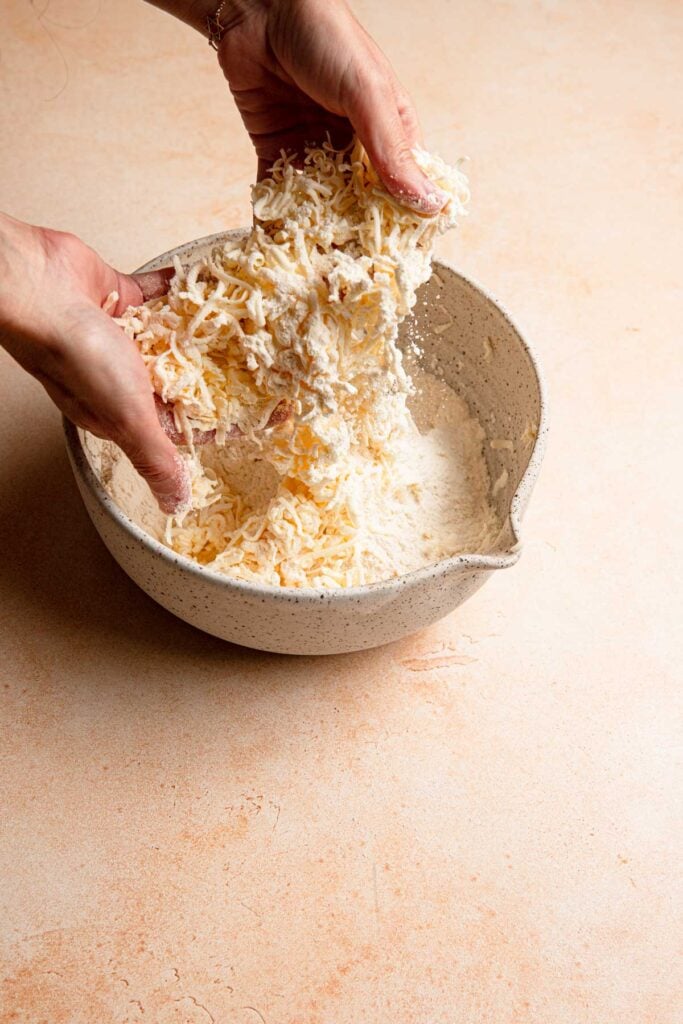 A hand tossing butter into flour.