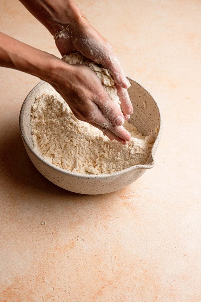 Hands rubbing butter into flour for scones.