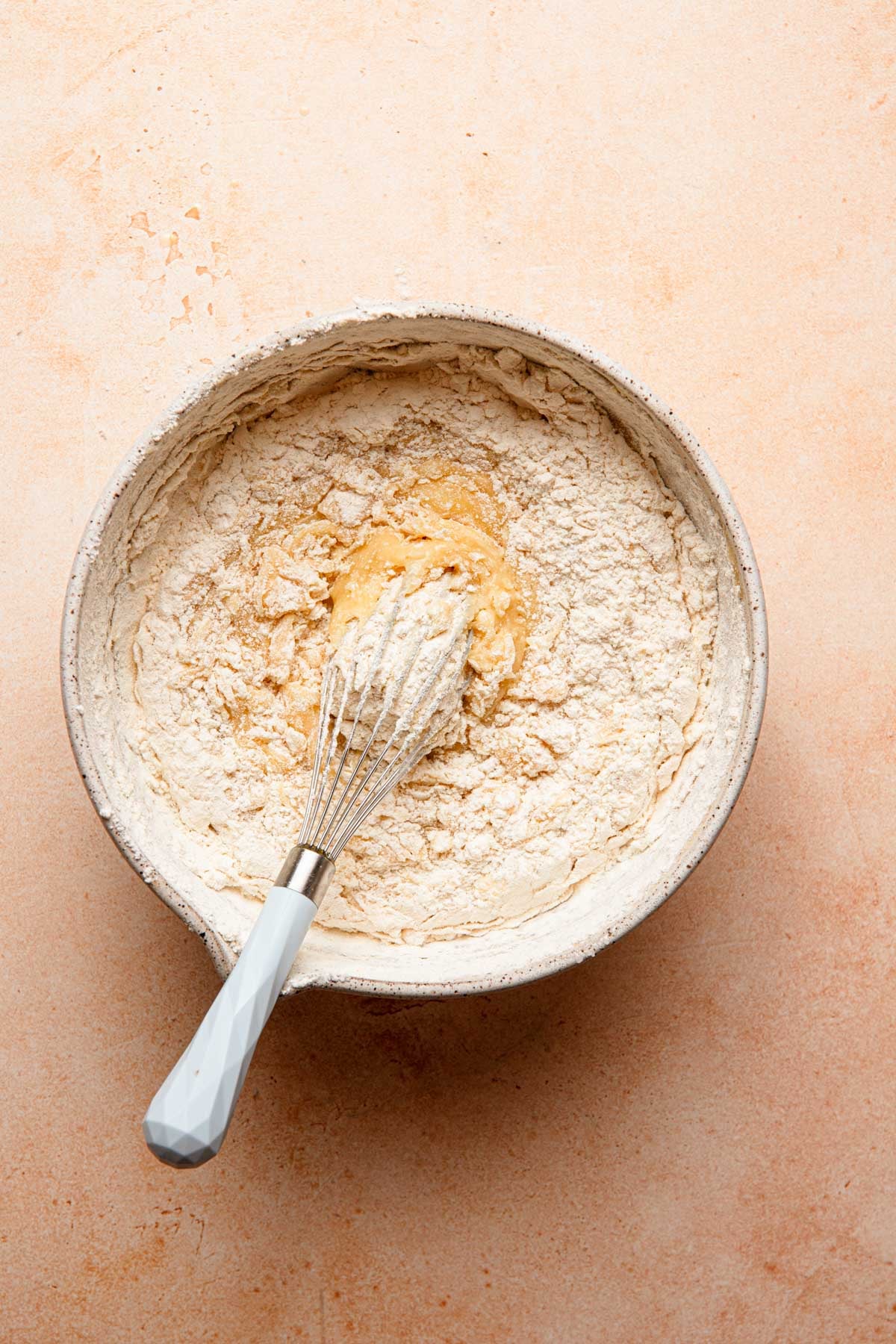 A mixing bowl with flour mixed into butter and egg mixture.