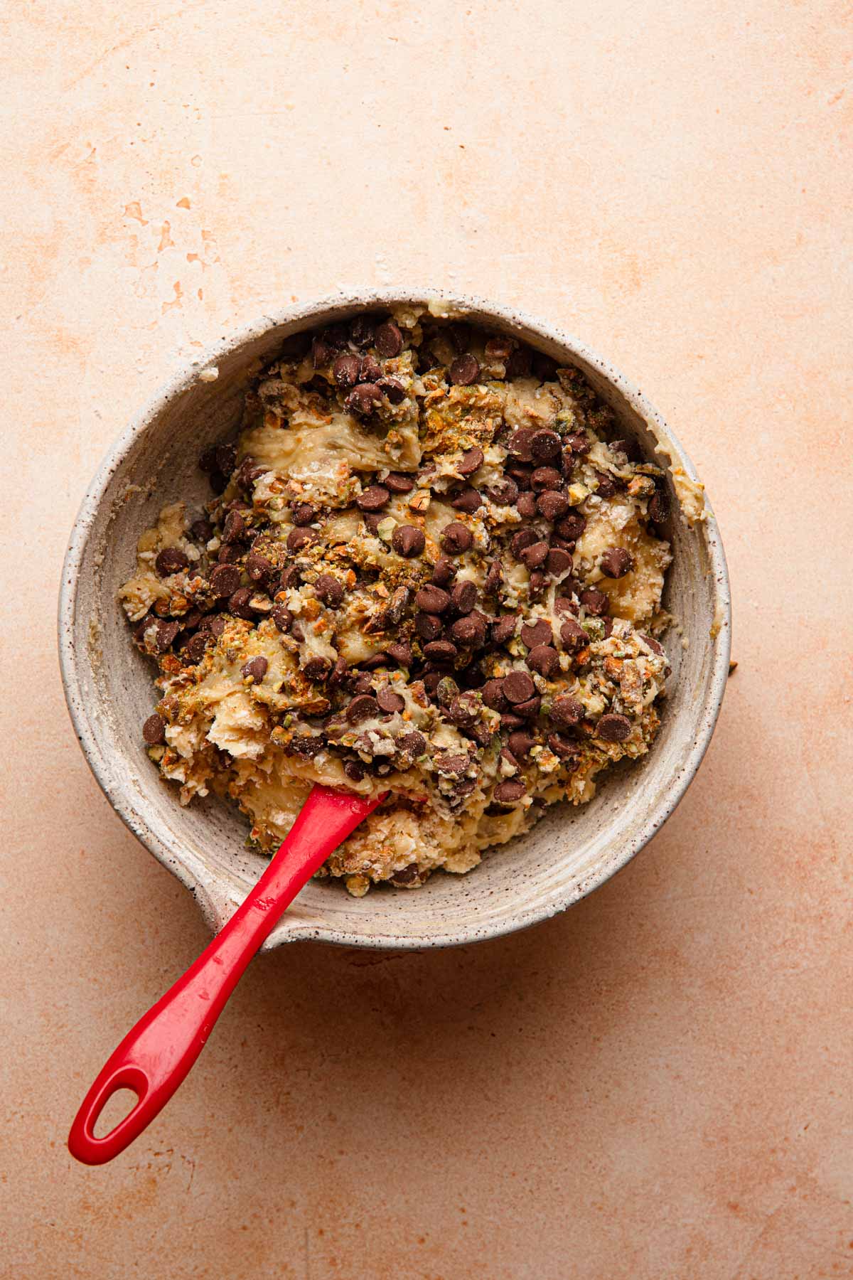 A raw batter in a mixing bowl and chocolate chips.